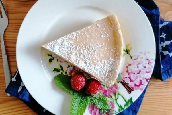A slice of pie on a plate with strawberries and powdered sugar.