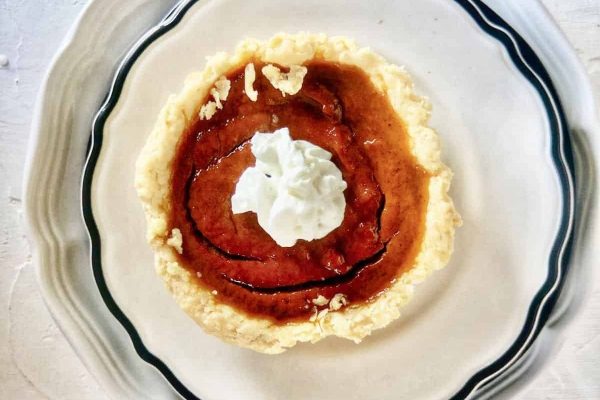 A pumpkin pie on a plate with whipped cream.