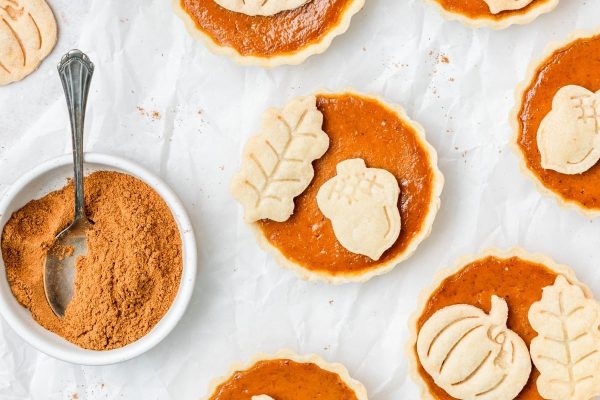 Pumpkin pie pies with powdered sugar and a spoon.