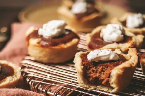 Pumpkin pies with whipped cream on a cooling rack.