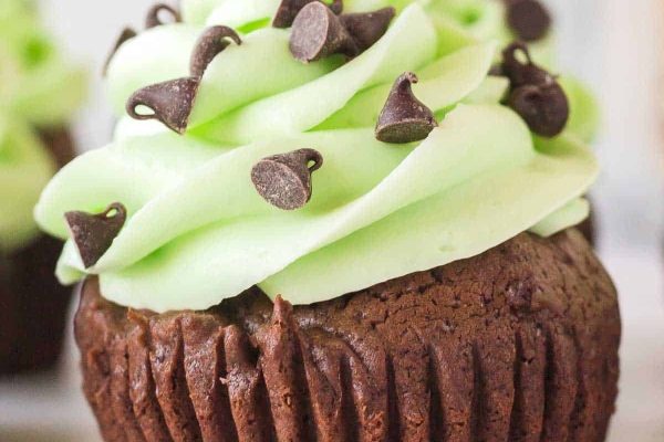 Christmas cupcakes decorated with green frosting and chocolate chips.
