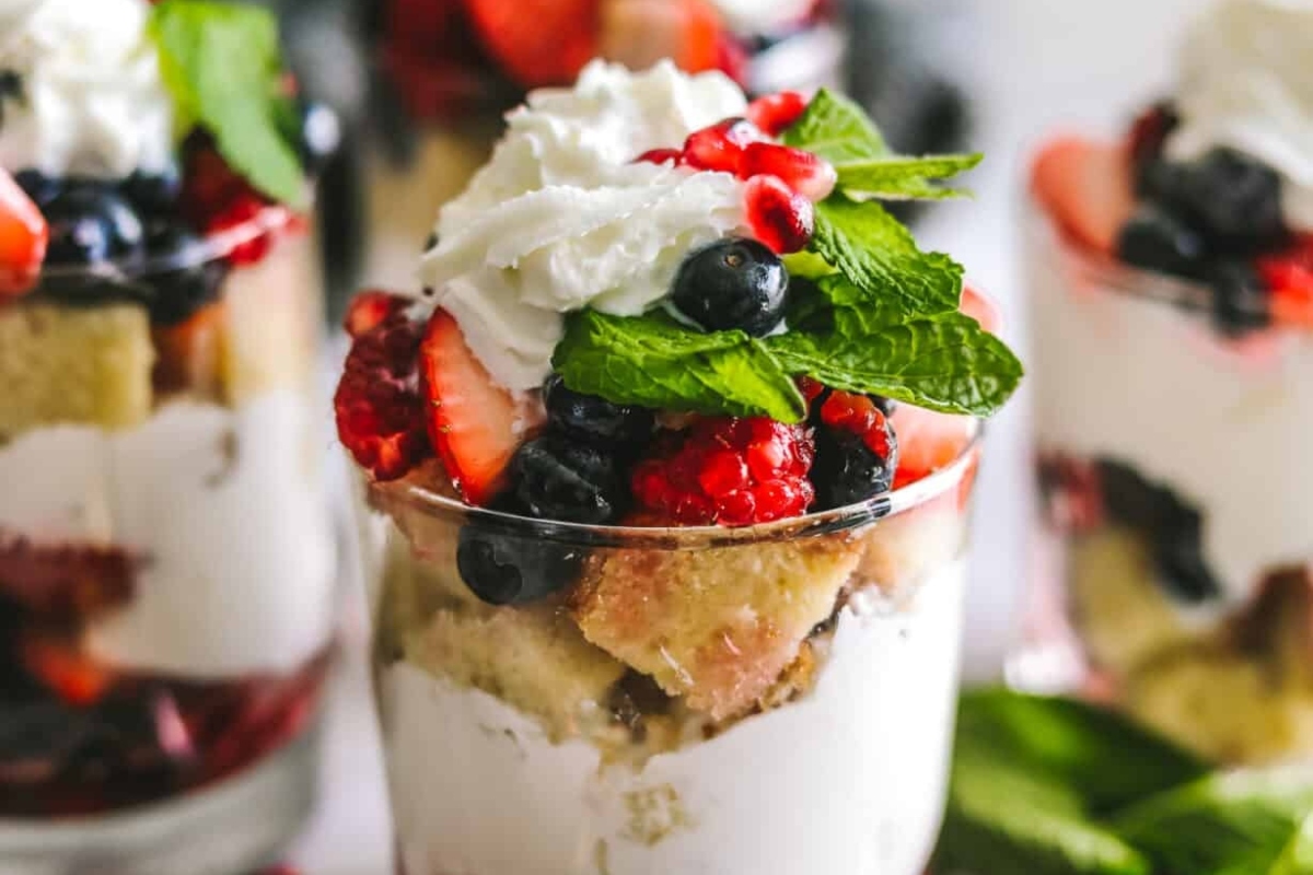 A Christmas berry trifle in a glass with whipped cream and berries.