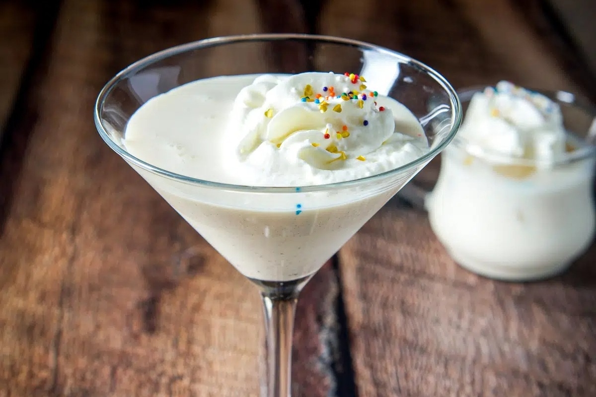 A Christmas-themed martini glass with whipped cream and sprinkles.