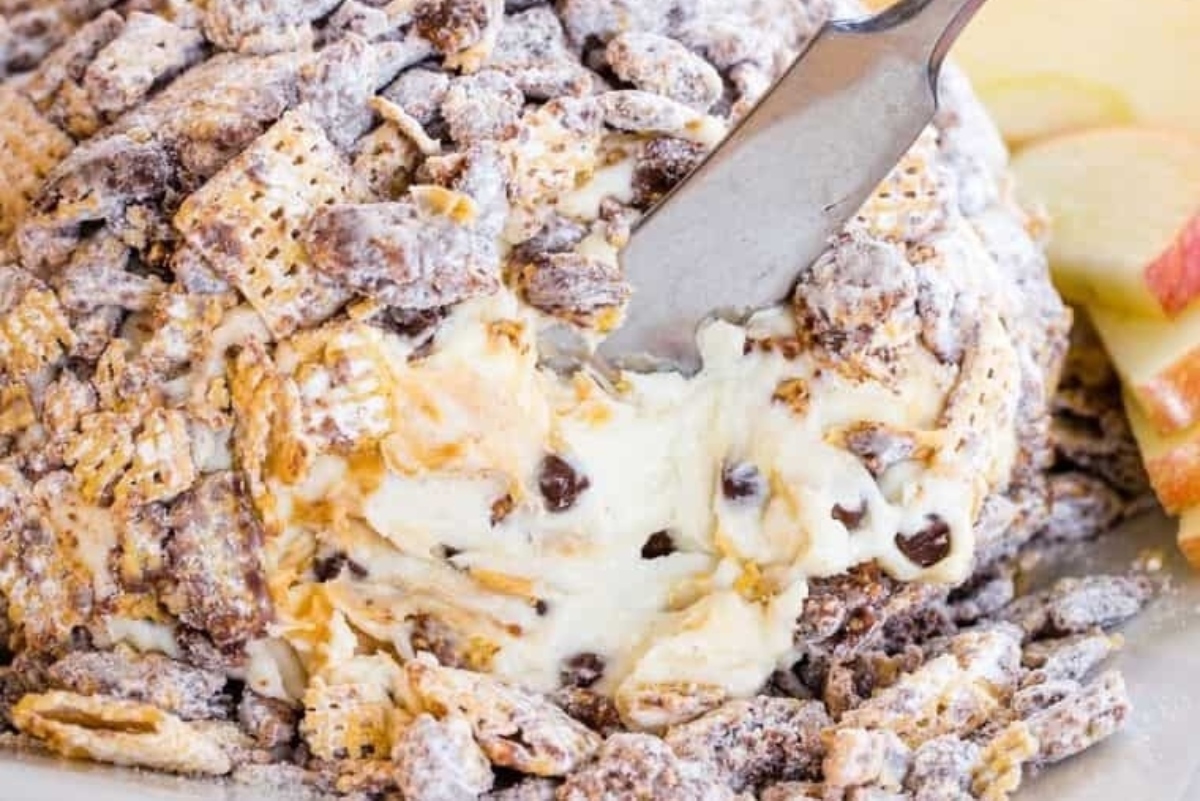 A slice of apple cranberry cheesy ball with a fork. This delectable treat is a cheese ball recipe that combines the flavors of apple and cranberry for a delightful twist. Enjoy it with your