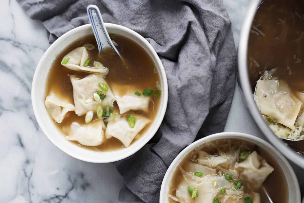 Two bowls of soup with dumplings in them.