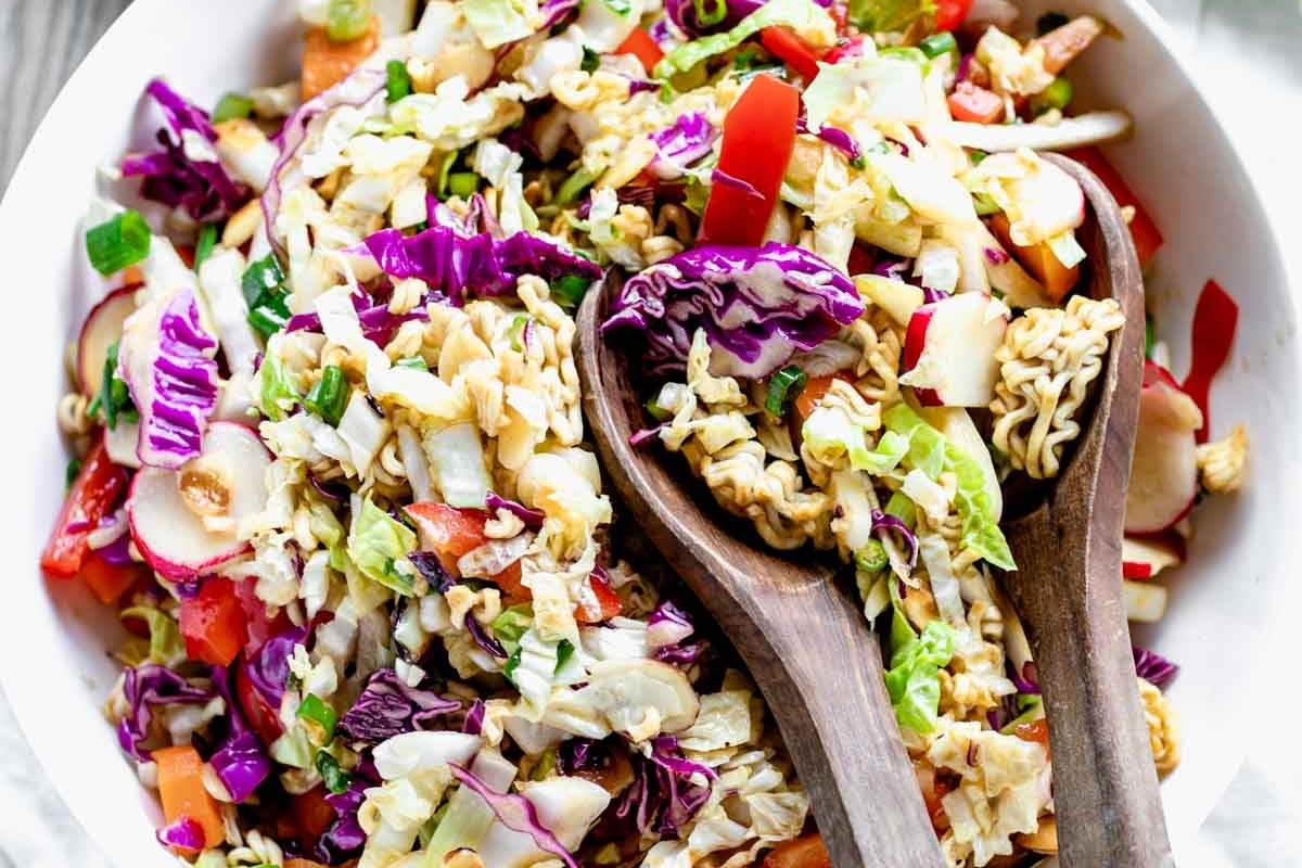 A make-ahead Asian noodle salad served in a bowl with wooden spoons.