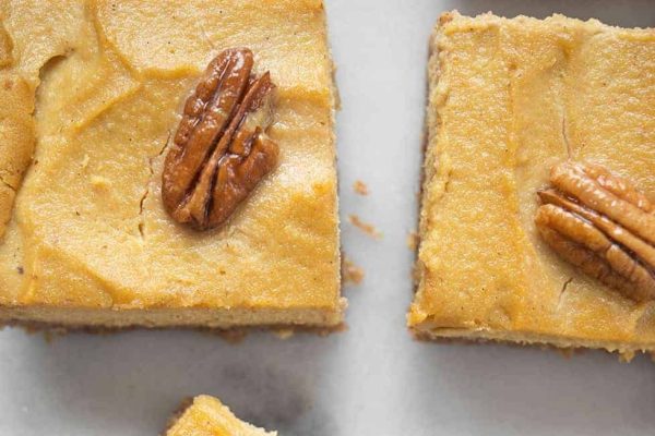 Pumpkin cheesecake bars with pecans on top.