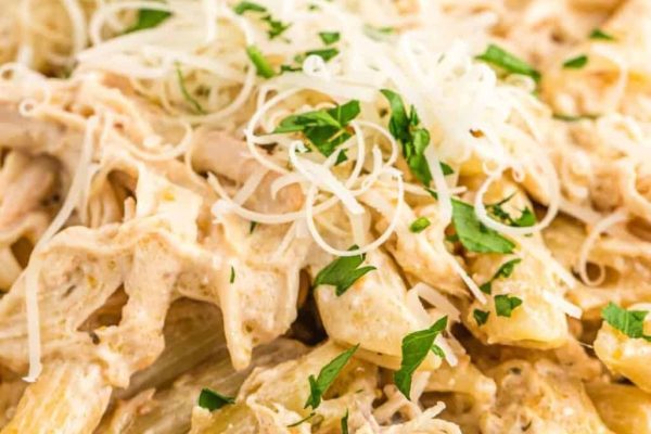 A close up of chicken pasta with parmesan cheese and parsley.