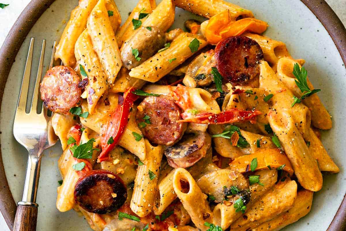 Penne pasta with sausage and peppers on a plate.
