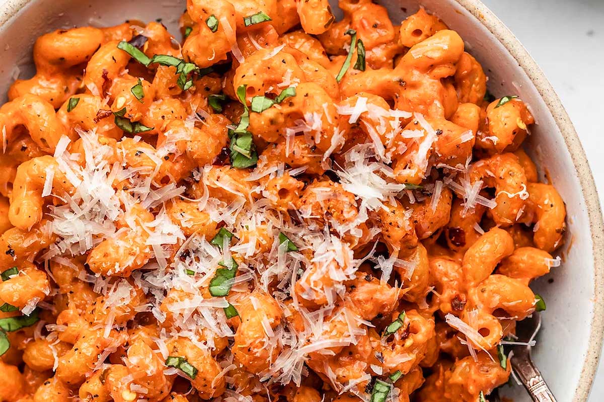 A bowl of pasta with sauce and parmesan cheese.