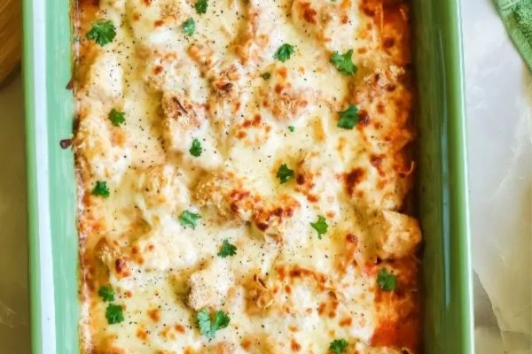 Cheesy chicken lasagna in a green baking dish.