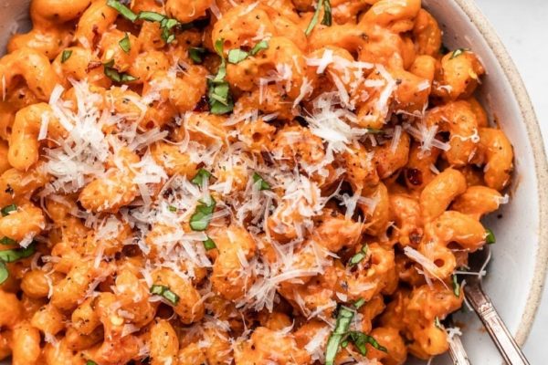 A bowl of pasta with tomato sauce and parmesan cheese.