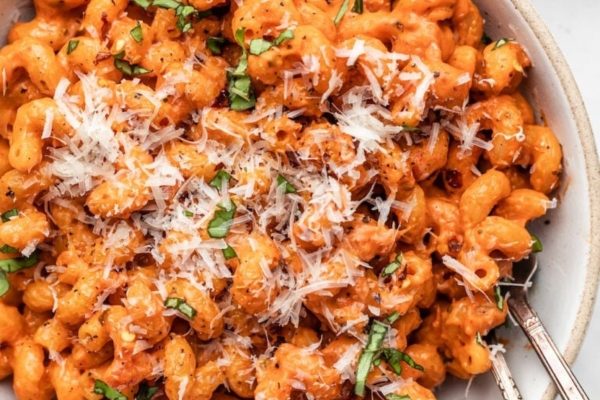 A bowl of pasta with sauce and parmesan cheese.