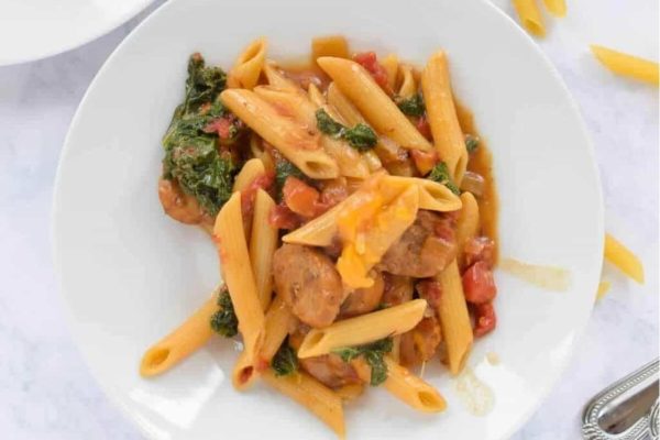 Parents Love: Penne with sausage and spinach on a white plate is a delicious and hearty meal that parents will adore. 
Kid Friendly Recipes: Penne with sausage and spinach on a white plate is