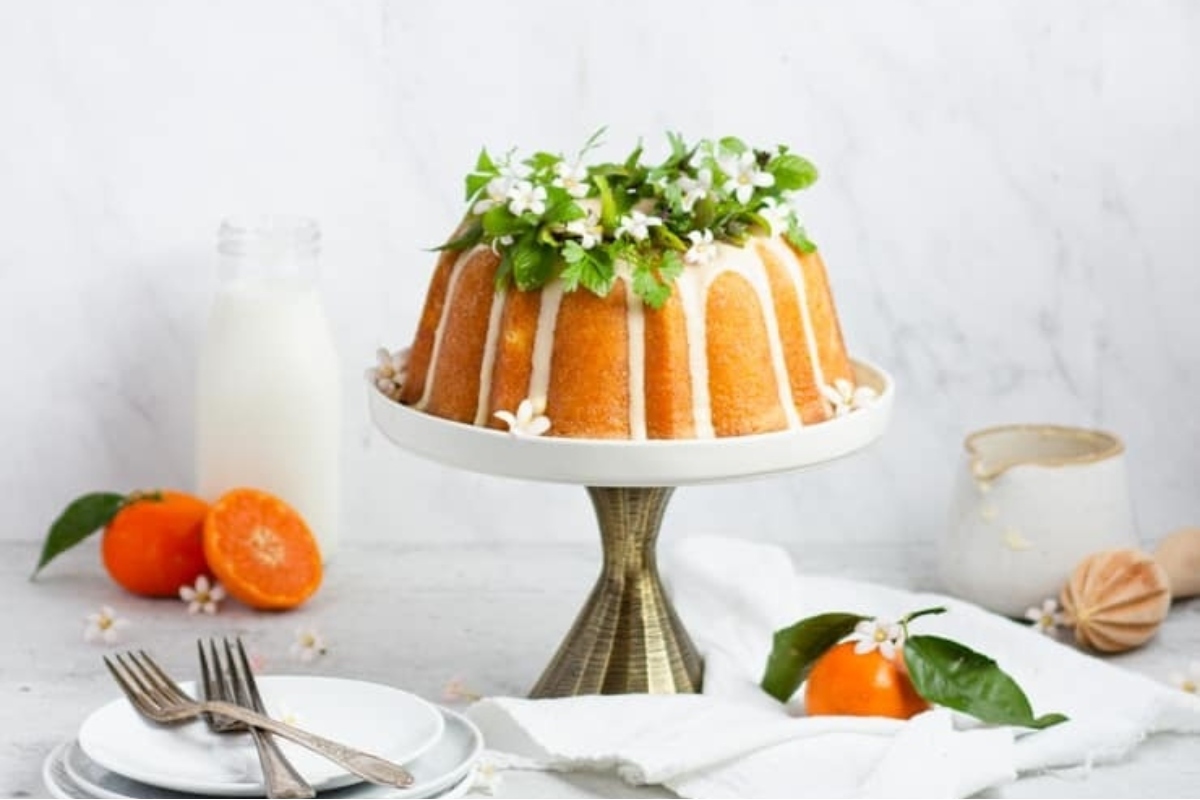A delightful Bundt cake adorned with juicy oranges and vibrant flowers.