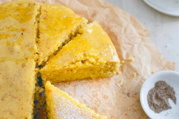 A slice of yellow cornbread is sitting on top of a piece of paper.