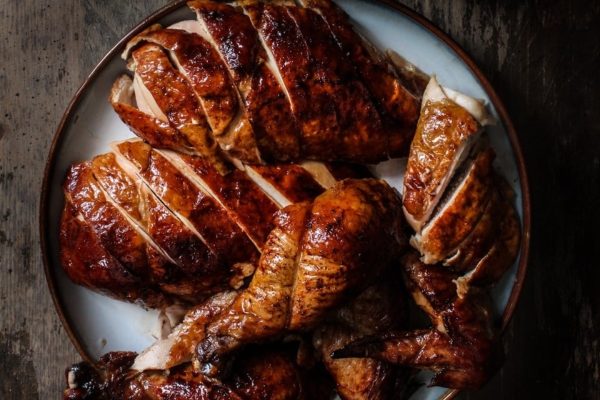Roasted chicken on a plate on a wooden table.