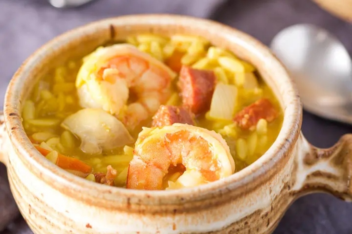 A bowl of shrimp and rice soup with a spoon.