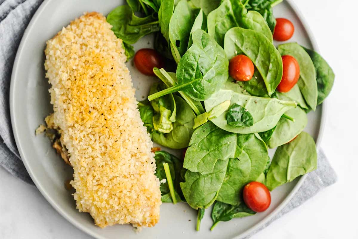 A plate with a piece of fish and a salad.