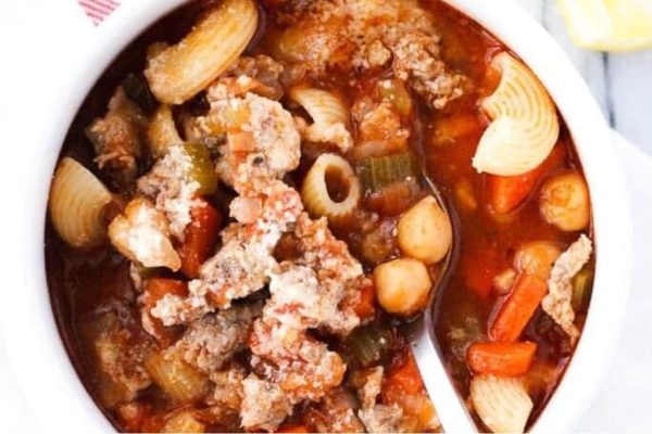 A bowl of pasta soup with meat and vegetables.