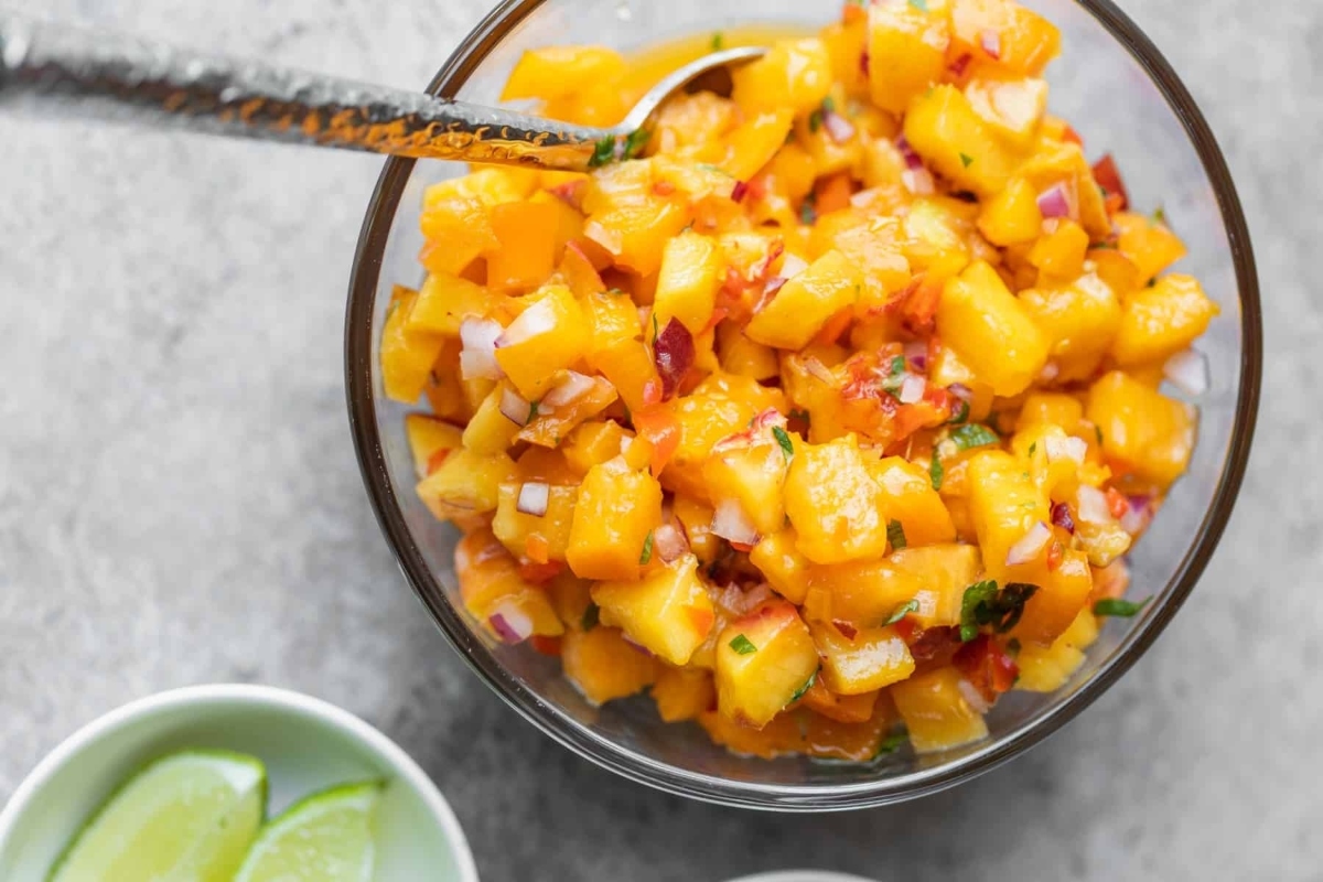 Peach salsa in a bowl with a spoon.