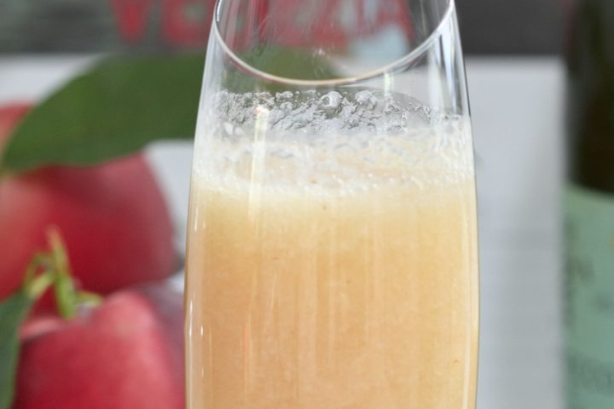 A glass of bubbly Champagne with apples in it.