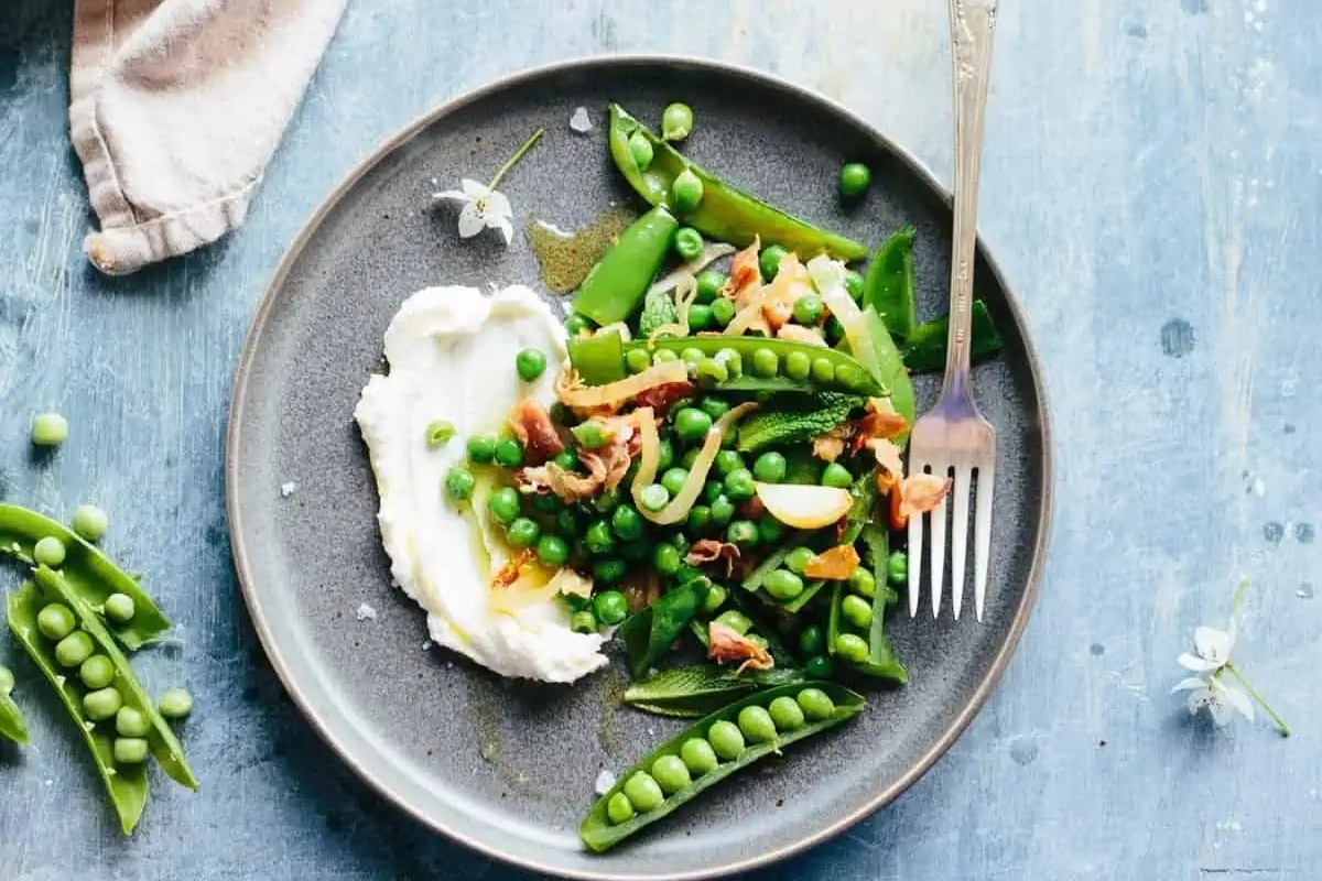 A plate with frozen peas and cream on it.