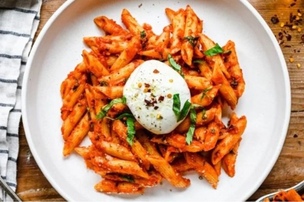 A delicious pasta recipe featuring a plate of pasta with tomato sauce and a dollop of ricotta.