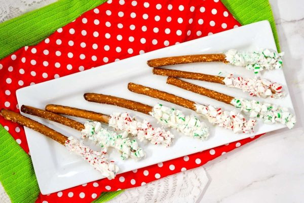 Christmas pretzels on a plate with icing and sprinkles.