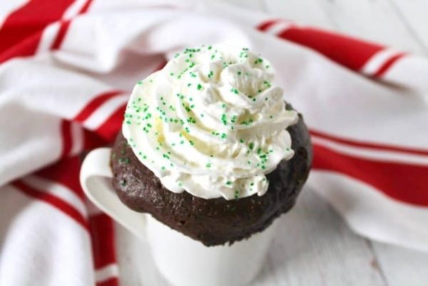 A chocolate cupcake topped with whipped cream and sprinkles.