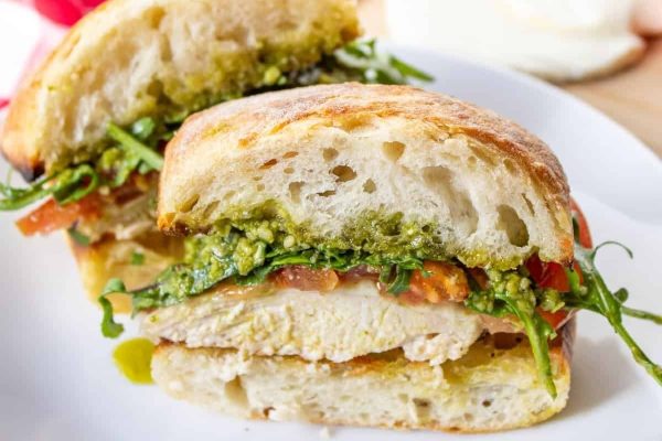 Chicken pesto sandwich on a white plate.