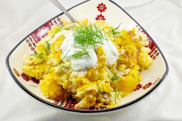 A bowl of mashed potatoes with sour cream and dill.