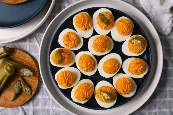 Deviled eggs on a plate with pickles, perfect for a potluck or Thanksgiving gathering.