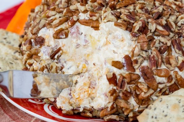 Cheese Ball Recipe: A delicious appetizer featuring a flavorful cheese ball garnished with pecans and served with crackers on a plate.