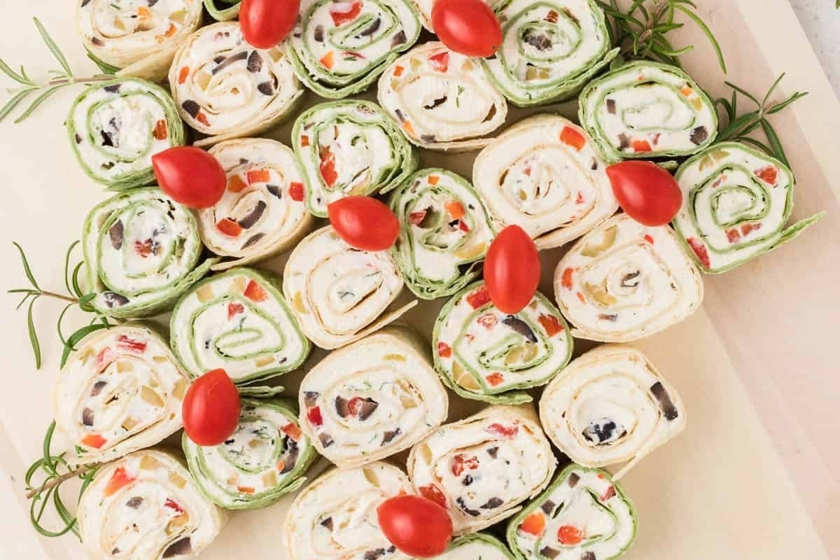 A festive charcuterie board adorned with rolls, tomatoes, and vibrant vegetables is the perfect addition to your Christmas gathering.
