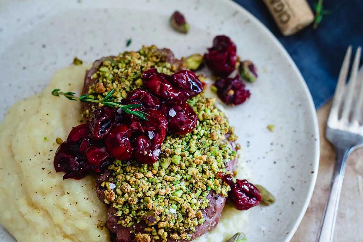 A romantic date night dinner featuring a delicious plate of steak accompanied by creamy mashed potatoes and tangy cranberries.