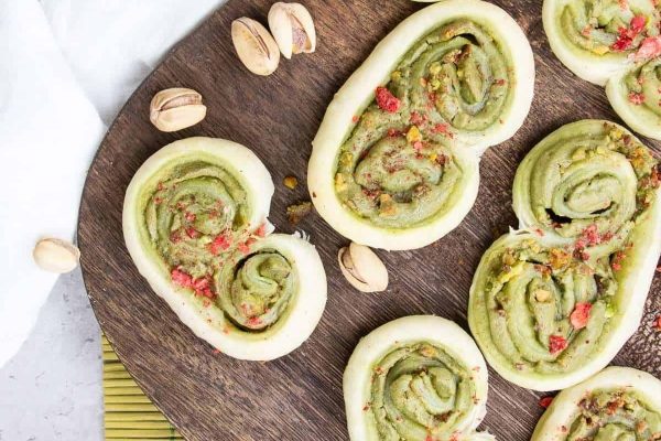 Heart shaped pistachio and pistachio cookies on a wooden cutting board.