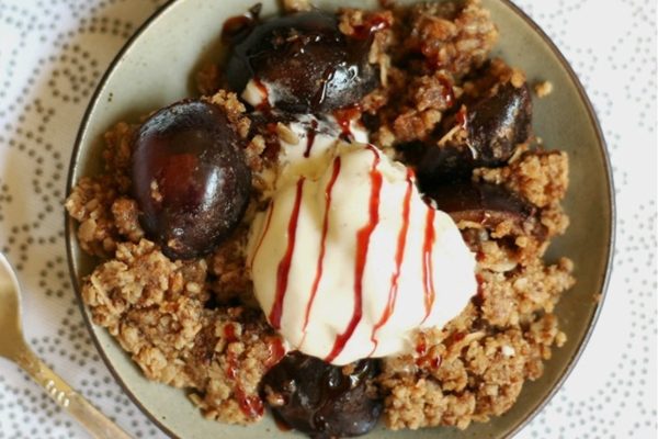 Plum crumble with ice cream on a plate.
