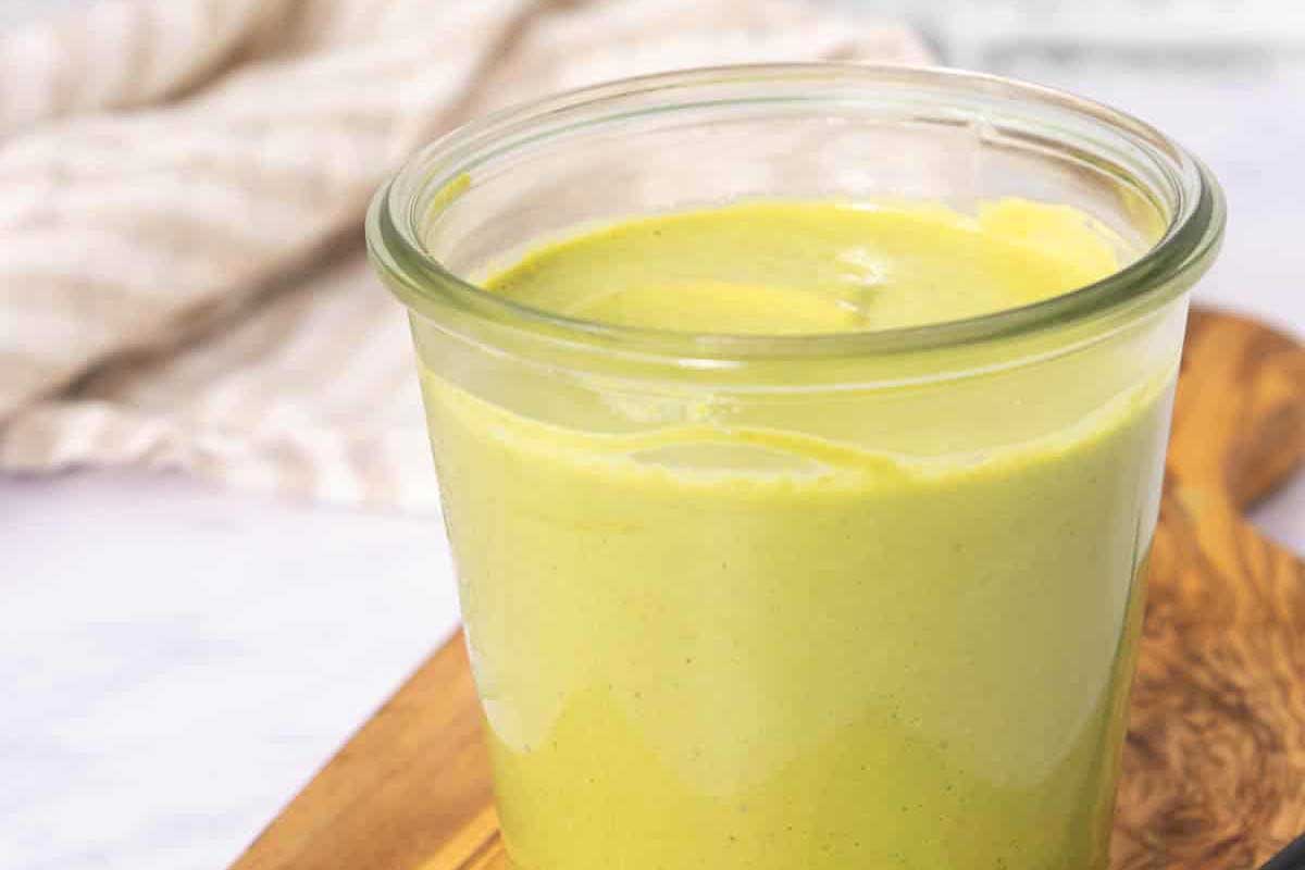 A green smoothie in a jar on a cutting board.