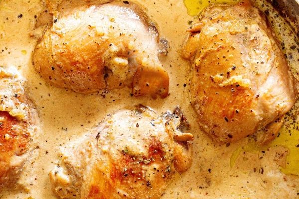 Chicken breasts in a pan with sauce.