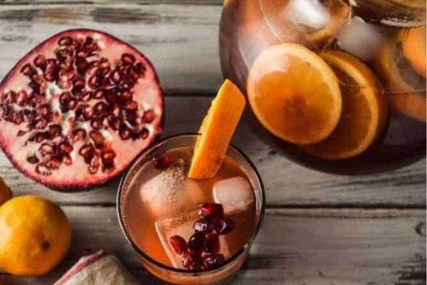 A pitcher of pomegranate sangria with orange slices.