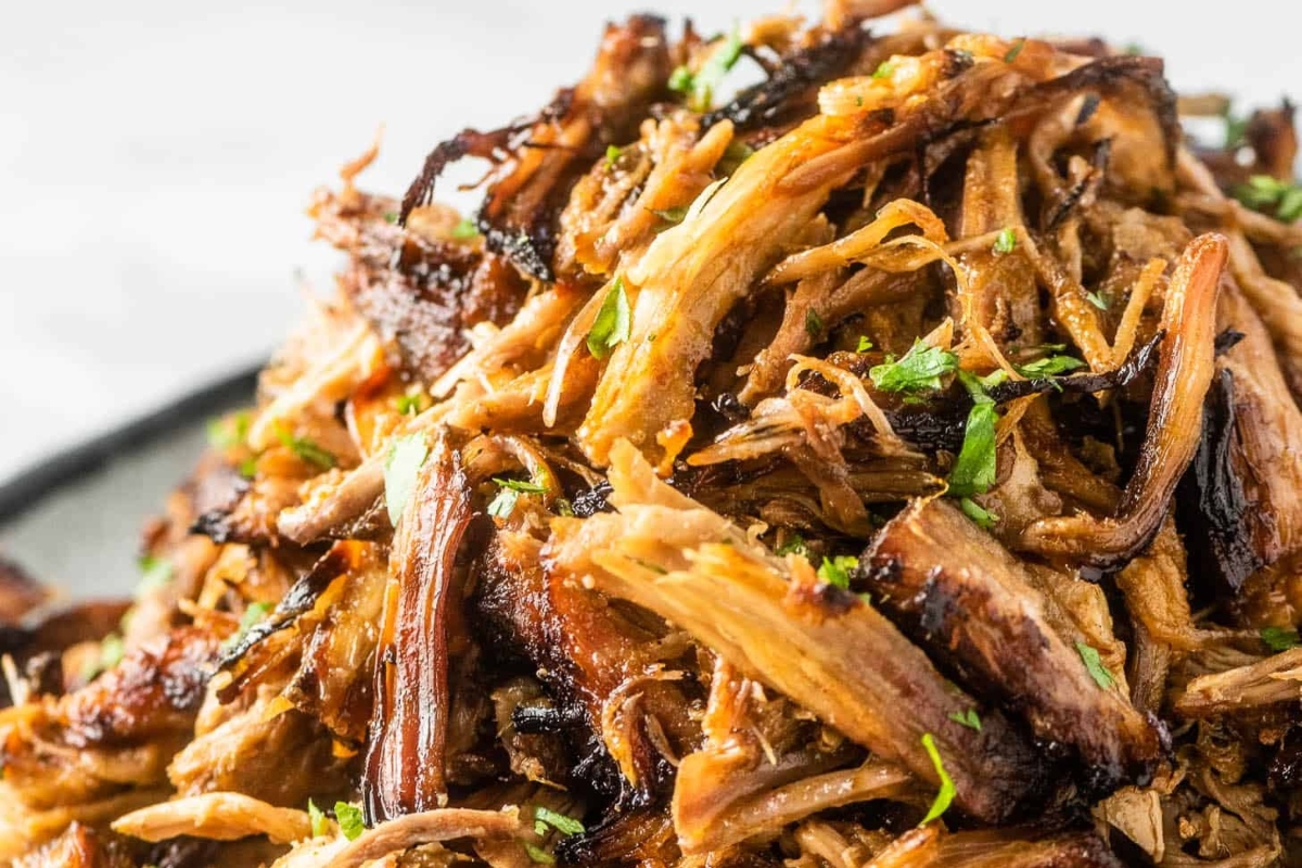 A savory pile of pulled pork, perfect for dinner on a plate.