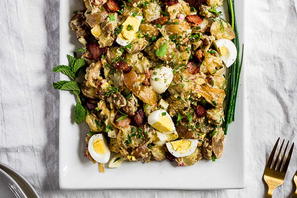 A plate of potato salad with bacon and eggs.