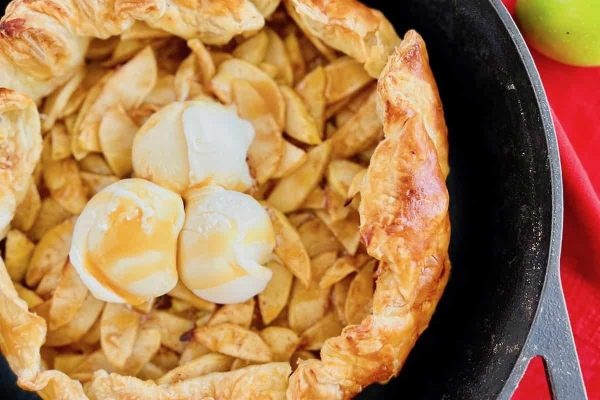 An apple pie in a skillet with a scoop of ice cream.