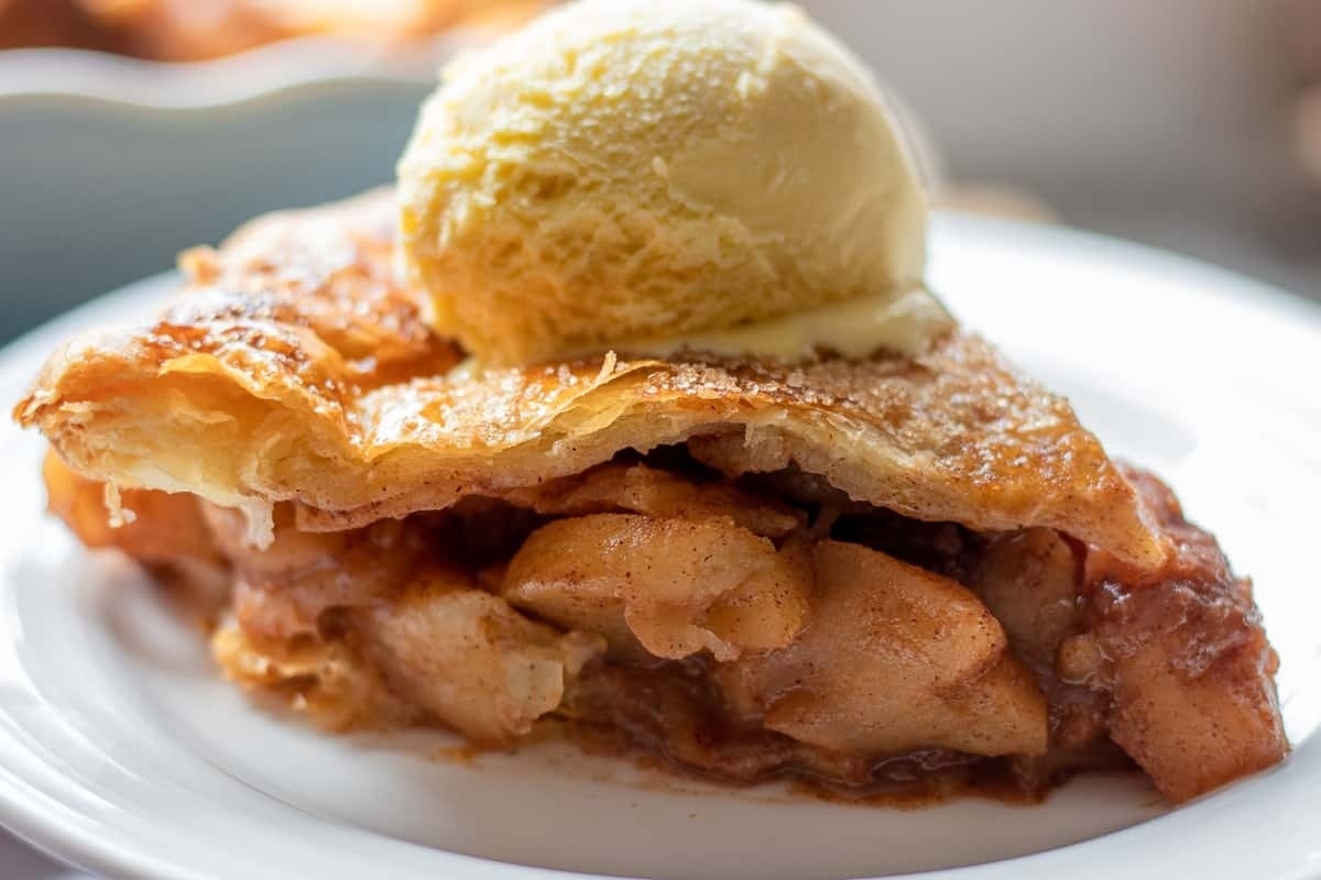 A slice of apple pie with ice cream on a plate.