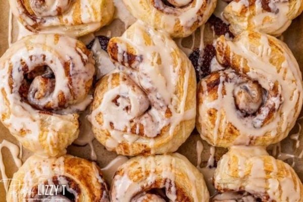 Cinnamon rolls with icing on a baking sheet.