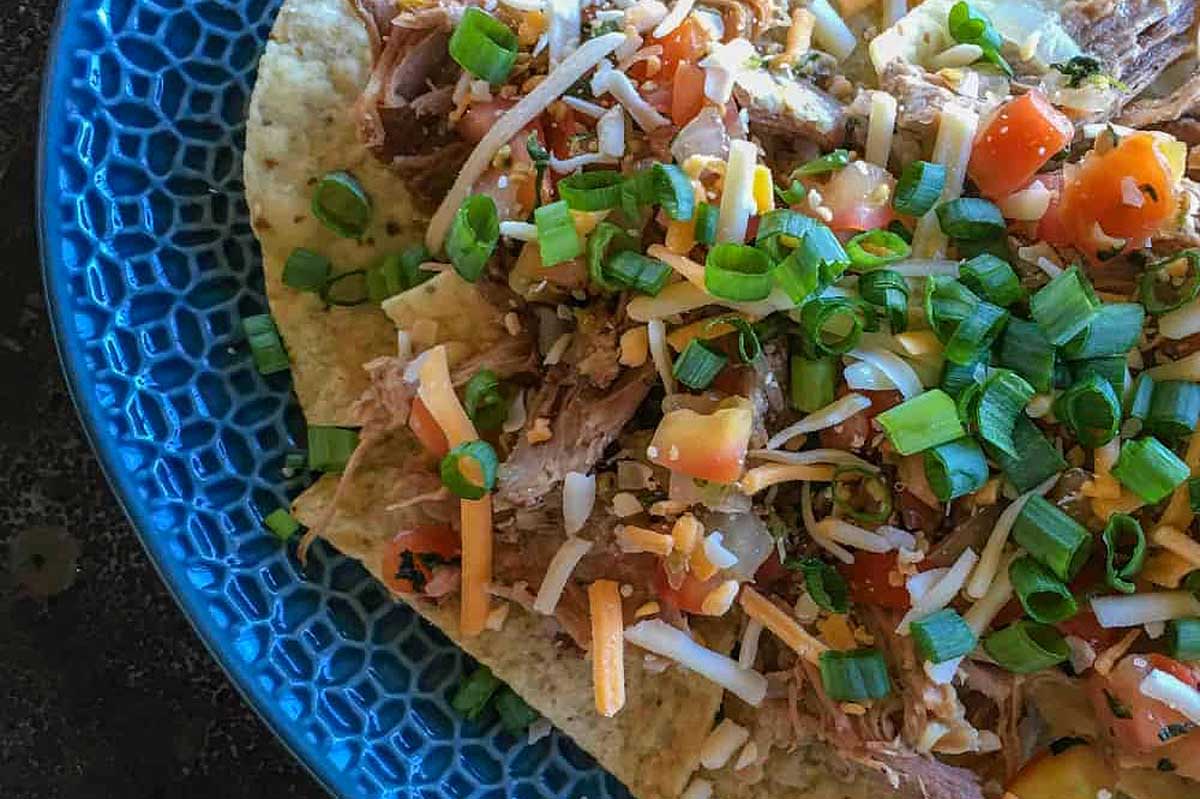 A delicious plate of nachos, piled high with mouthwatering meat and vegetables, perfect for indulging in as pub or bar food.