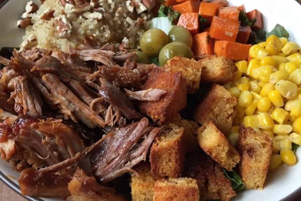 A bowl of pulled pork, corn, and carrots.