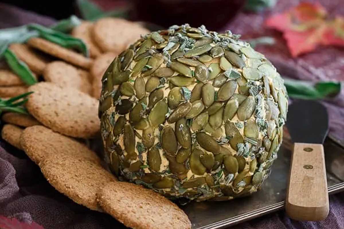 A pumpkin cheese ball on a tray with crackers.