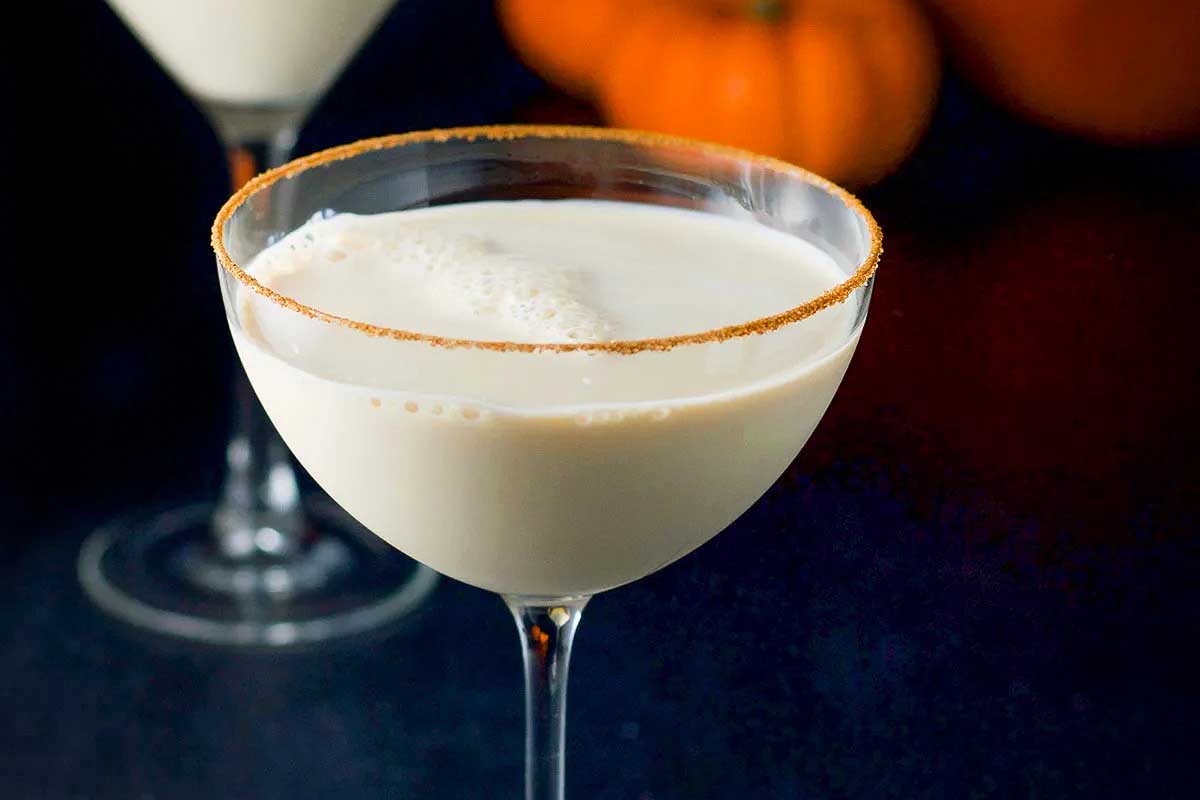 Two fall glasses of pumpkin spice latte with whipped cream.